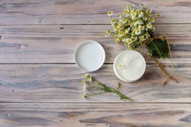 Papatya buketi ve ahşap bir masa üzerinde kokulu vücut kremi