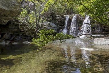 Güneşli bir günde bir şelale ile küçük dağ nehri (Yunanistan, An