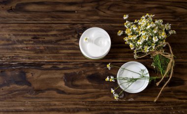 Papatya buketi ve ahşap bir masa üzerinde kokulu vücut kremi