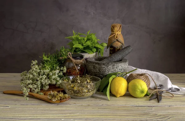 Различные травы и специи, лимоны и оливковое масло на деревянном столе — стоковое фото