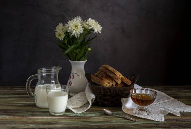 Taze ekmek, bal ve süt ve beyaz papatyalar ile bir vazo.