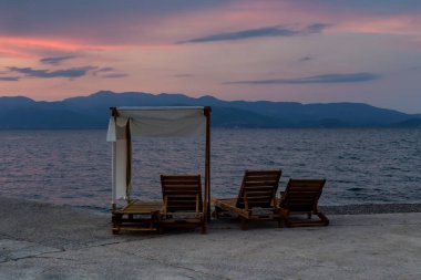 Bir yaz günü gün batımında dağlar, deniz ve boş güneşlik manzarası (Phthiotis, Yunanistan)