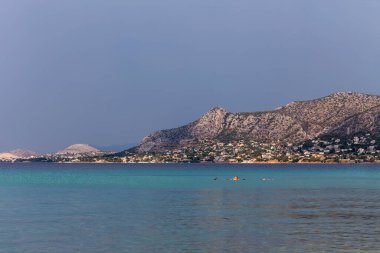 Güneşli bir yaz gününde güzel bir çakıl taşı plajı, dağlar ve deniz manzarası (Salamis Adası, Yunanistan)