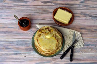 Ulusal Rus mutfağı. Bir sürü taze, sıcak, fırında krep, yeşil tabakta tereyağı ve ahşap bir masada yakın plan bir kasede reçel..