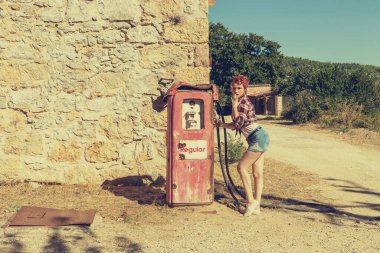 Güneşli bir sonbahar gününde parktaki eski bir benzin istasyonunda genç ve güzel bir mandal kızı.