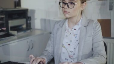 Gözlüklü genç office kız ofiste bilgisayar çalışır. 4k