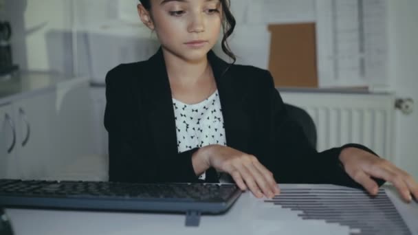 Симпатичная успешная школьница охотно работает с компьютером и улыбается на камеру — стоковое видео