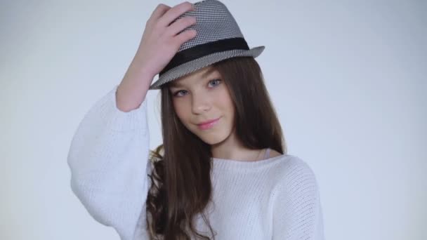 Hezká mladá dívka si hraje s kloboukem a nosí na hlavě s roztomilý úsměv — Stock video