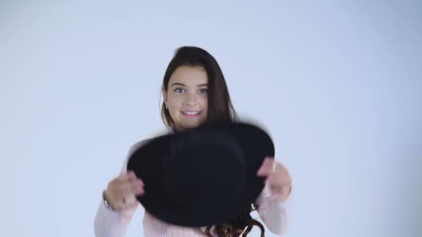 Csinos, fiatal lány játszik a kalapját, és hordja fejét, aranyos mosoly — Stock videók