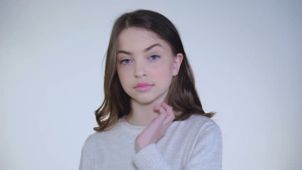 Привлекательная девушка кладет волосы за ухо и серьезно смотрит в камеру — стоковое видео