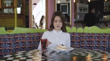 Pretty genç kız meyve suyu içecekler ve lezzetli tatlı 4 k kafede yiyor
