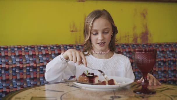 Menina bonita comendo sobremesa saborosa e olhando para a janela. 4K — Vídeo de Stock