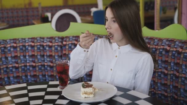 Feliz joven bebe un jugo y come sabroso postre en la cafetería 4K — Vídeo de stock