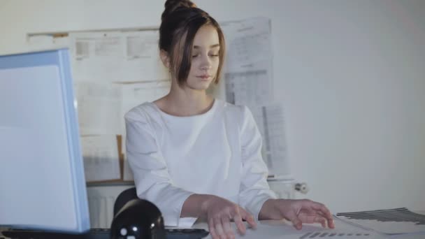 Pretty young girl is busy at workplace and smiles at camera. — Stock Video