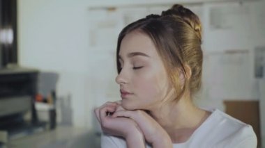 Sevimli kız işyerinde oturur, el ve kamera gülümsüyor üzerinde eğilir.