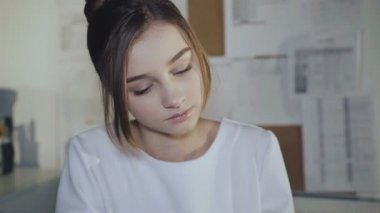 Sevimli kız işyerinde oturur, el ve kamera gülümsüyor üzerinde eğilir.