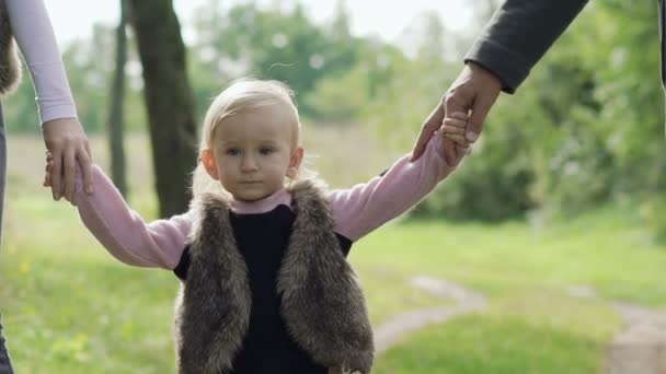 Portrait of little kid, who is led by parents in their hands. Slowly — Stock Video