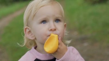 Mavi gözlü çocuğun yakın çekim portre parkta balon patlatmaya çalışır. Yavaş yavaş