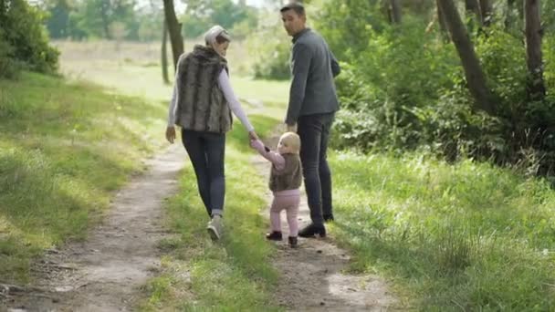 Ευτυχισμένη οικογένεια βόλτες με το μικρό παιδί τους σχετικά με τη φύση. Σιγά-σιγά — Αρχείο Βίντεο