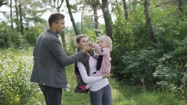 Família feliz descansar sobre a natureza com criança, soprando e pegando bolhas — Vídeo de Stock