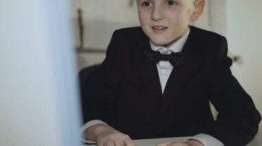 Takım elbiseli küçük neşeli çocuk bilgisayar oyunu oynar ve ofiste kazanır. 4k