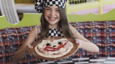 Genç kız gülümsüyor pizzayla kameraya gösterir. Yavaş yavaş