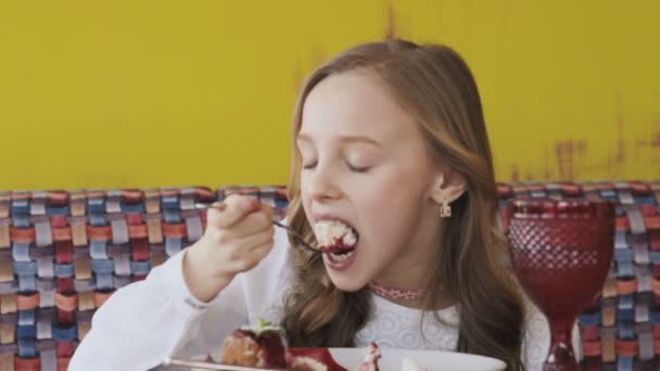 Gelukkig jong meisje eten smakelijk dessert en glimlachend in de camera. Langzaam — Stockvideo