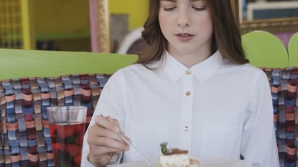 Boldog, fiatal lány, evés a finom desszert, és mosolyogva kamera — Stock videók