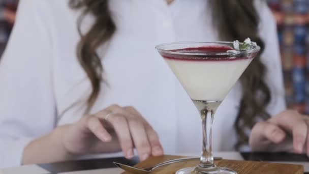 Gelukkig meisje met glimlach draaiingen cocktail gelei op een tafel in café — Stockvideo