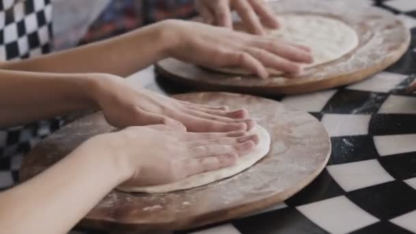 Дві веселі дівчата в уніформі готують піцу на майстер-класі начальника кафе . — стокове відео
