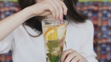 Limonata tübül ile karıştırarak ve kameraya gülümseyen güzel kız