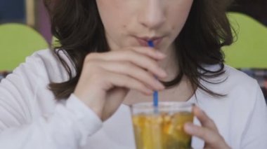 Görünümü bir kız kadar yakın hareket ediyor ve kafede tübül ile limonata içer