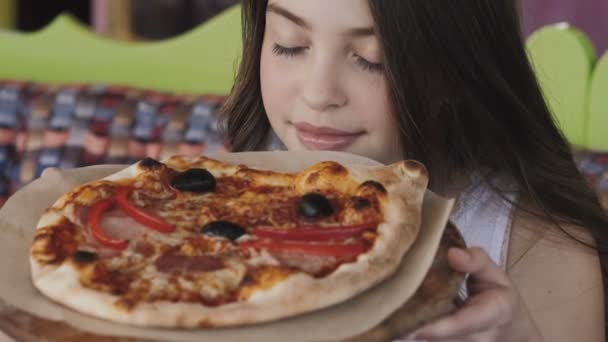 Nahaufnahme eines hübschen jungen Mädchens, das den Geruch einer Pizza genießt. langsam — Stockvideo
