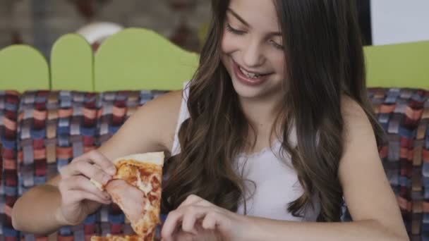 Close-up van portret van mooie jonge meisje eet pizza met verrukking in café — Stockvideo