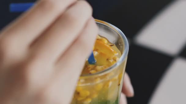Vista de cerca de chica agita y bebe limonada con túbulo en la cafetería — Vídeo de stock
