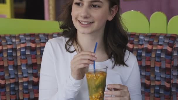 Zamknij widok dziewczyny wzbudza i pije lemoniadę z kanalików w kawiarni — Wideo stockowe