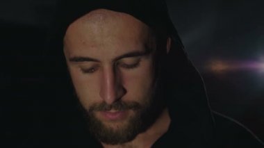 Güçlü kamera siyah pelerin terli bir adamın karanlıkta bakın. 4k