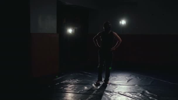 Человек в шлеме тренируется в темной студии с подсветкой 4К — стоковое видео