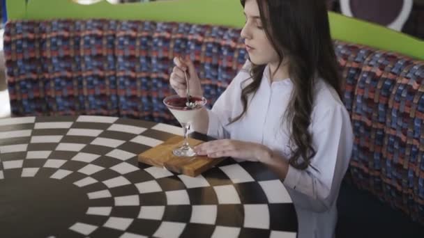 Ευτυχισμένος κορίτσι τρώει νόστιμα ζελέ σε ένα τραπέζι για καφέ. 4k — Αρχείο Βίντεο