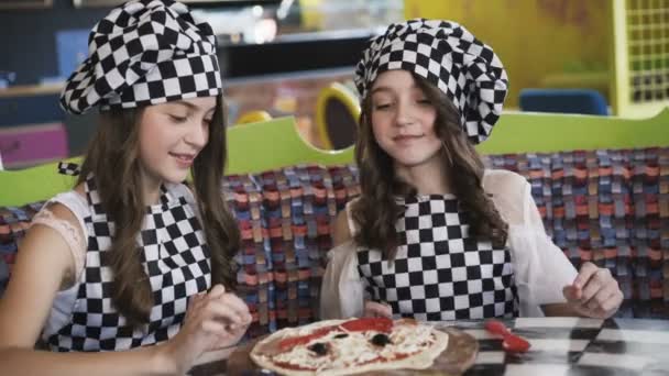 Dos muchachas alegres en uniforme que cuecen la pizza en la clase maestra en la cafetería 4K — Vídeos de Stock