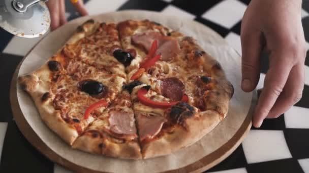 Draufsicht einer Person, die eine leckere Pizza mit einem Pizzaschneider in Scheiben schneidet — Stockvideo