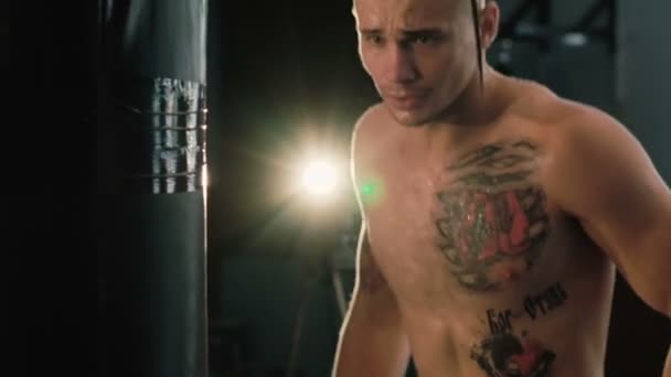 Sem pelos com pigtail em uma cabeça e tatuagens, saco de perfuração de treinamento de lutador livre . — Vídeo de Stock