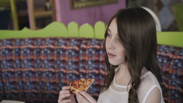 Una chica muy joven comiendo pizza en la cafetería. 4K — Vídeo de stock