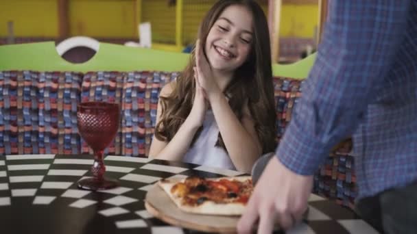 Una chica guapa mirando cómo el camarero le corta una pizza en la cafetería. 4K — Vídeo de stock