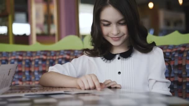 Menina bonita lendo o menu e fazendo uma ordem. 4K — Vídeo de Stock