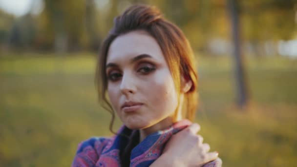 Portrait of a young brunette flirts at camera with her eyes in sunny autumn park — Stock Video