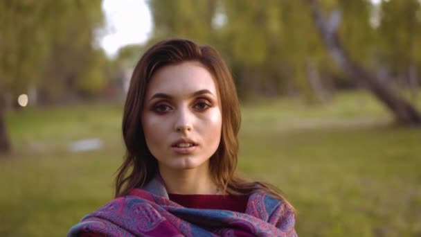 Portrait of a young confident girl looks at camera in sunny park — Stock Video