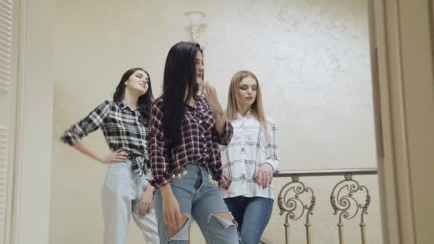 Tre vackra flickor står i pose på trappor i hem. Långsamt — Stockvideo
