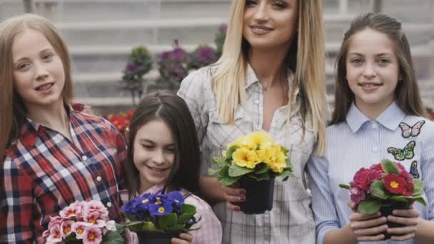 Vier meisjes met bloempotten in handen kijken camera glimlachen — Stockvideo
