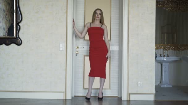 Svůdné modrýma očima blondýnka v červených šatech pózuje na kameru. 4k — Stock video